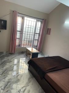 a bedroom with a bed and a table and windows at Ooty Peak view villa in Ooty