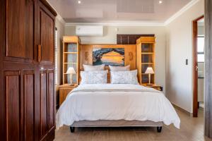 a bedroom with a bed with a wooden headboard at Sea Spray Self Catering in Duyker Eiland in Britannia Bay
