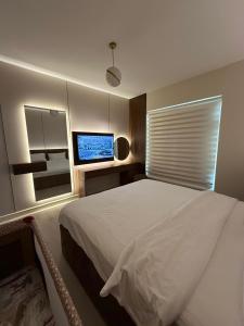 a bedroom with a bed and a flat screen tv at شقة البيلسان فيو Baylasun View in King Abdullah Economic City