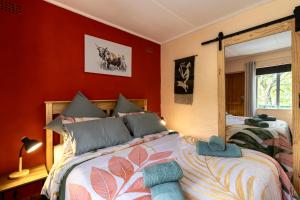two beds in a bedroom with red walls at Birdsong Cottage in Howick