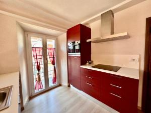 eine Küche mit roten Schränken und einer Spüle und Fenstern in der Unterkunft Chalet Ame in Bormio