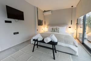 a bedroom with a bed with white sheets and a tv at Loft 77 Patras in Patra