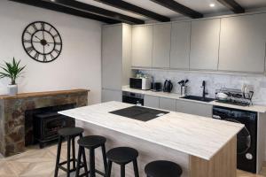 a kitchen with a counter with stools and a fireplace at Valdermosa in Newlyn