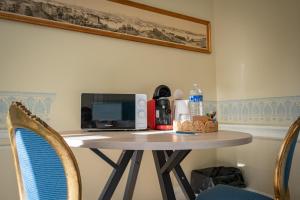 a small table with a microwave and a table with chairs at Le Palais de la Cathédrale in Saint-Omer
