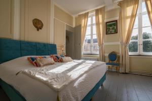 a bedroom with a large bed with a blue headboard at Le Palais de la Cathédrale in Saint-Omer