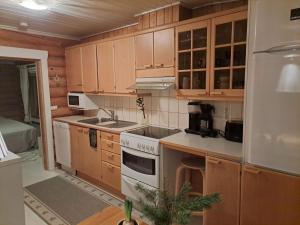 a kitchen with wooden cabinets and a white stove top oven at Kangasjärvi in Pudasjärvi