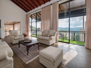 a living room with two chairs and a table and large windows at Swarga Villa in Kandy