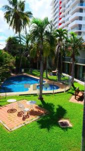 a swimming pool with palm trees next to a building at Motel 98 in Rockhampton