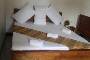 a bed with white pillows and two towels on it at Rose Lagoon Hotel in Vakarai