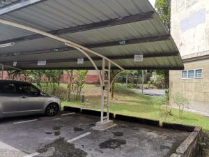 a parking lot with a car parked under a metal roof at Eden 8pax 3Rooms apartment near Kuching Airport in Kuching