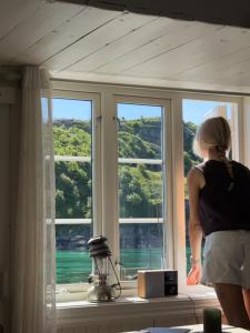 a woman looking out the window of a house at Sakrisøy Rorbuer in Reine