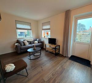 a living room with a couch and a tv at Appartement Ocean Breeze Nes Ameland in Nes