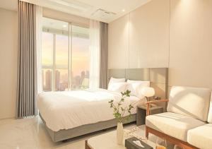 a bedroom with a bed and a chair and a window at Sota Suite Busan Seomyeon in Busan