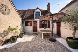 a patio with an umbrella in front of a house at Le Cottage des Chalands - classé 3 étoiles in Saint-Georges-sur-Cher