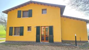 a yellow house with green shutters on it at La Nocina in Raggio