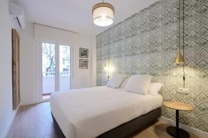 a bedroom with a white bed and a wall at MOON Apartments in Seville