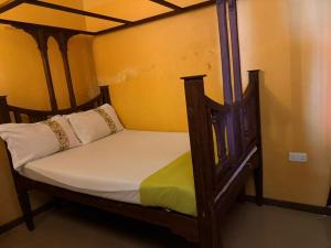 a bedroom with a wooden bed with white pillows at Busara house 2 in Zanzibar City