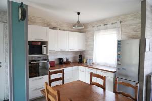 a kitchen with white cabinets and a table and a refrigerator at Le Petit Orme in Chartres +26 photos