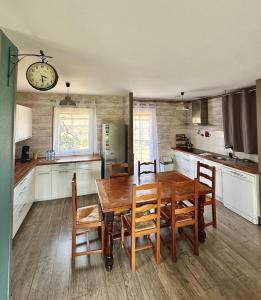 a kitchen with a wooden table and chairs and a clock at Le Petit Orme in Chartres