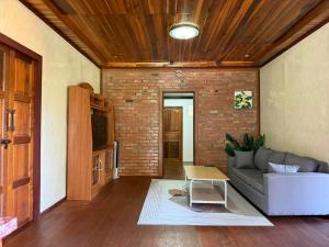 a living room with a couch and a brick wall at Cozy Beach House , 5 mn from the Sea -Self Check in in Ban Laem Sai