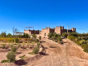 a dirt road in front of a large building at La Colline Verte Dar Ait El Abass in Ouarzazate