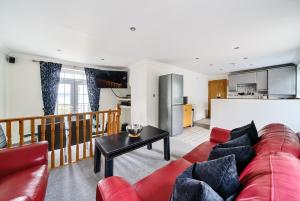 a living room with a red couch and a kitchen at Southover Beach in Woolacombe