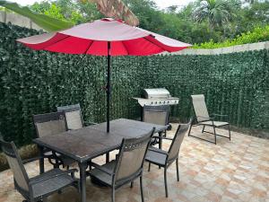a table and chairs with a red umbrella and a grill at Privat 3 bedroom apartment in Sosua