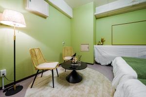 a bedroom with a bed and two chairs and a table at AoiResidence別邸葵 in Nagoya