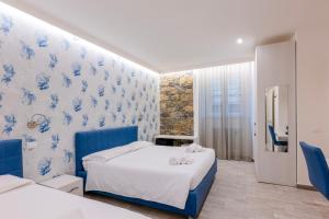 a bedroom with two beds and blue and white wallpaper at 5 Terre Lodge in La Spezia