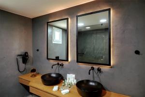 a bathroom with two black sinks and a mirror at Anemos Luxury Grand Resort in Georgioupolis