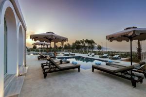 a pool with tables and chairs and umbrellas at Anemos Luxury Grand Resort in Georgioupolis