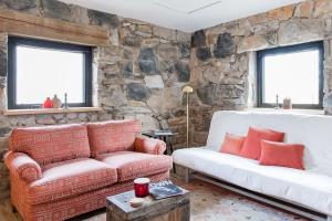 a living room with a couch and a stone wall at The Forest Door - Studio Suite in Stone Cottage in Tryon