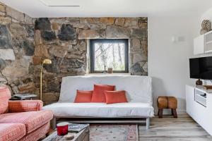 a living room with a white couch and a stone wall at The Forest Door - Studio Suite in Stone Cottage in Tryon