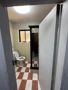 a bathroom with a toilet and a window and a tile floor at Longacres Cottage in Lusaka