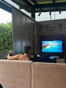a man laying on a couch watching a tv at Belvedere Suite Campestre in Alcalá