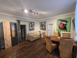 a living room with a table and chairs and paintings on the walls at Appartement Neckartal in Hirschhorn