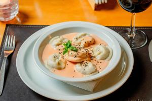 a bowl of dumpling soup on a plate with a wine glass at Hostería Varvarco in Varvarco