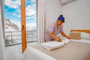 a woman putting towels on a bed in a room at Hostería Varvarco in Varvarco
