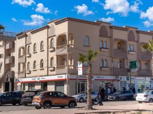 a large building with cars parked in a parking lot at Erraha Hostel Dakhla in Dakhla