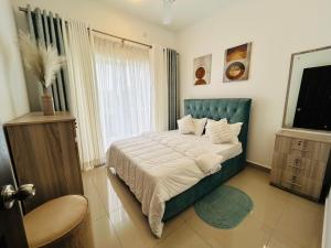 a bedroom with a bed with a blue headboard and a window at Santorini VIP Apartment Negombo in Negombo