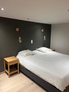 ein Schlafzimmer mit einem großen weißen Bett und einem Tisch in der Unterkunft Hotel Val De La Cascade in Stavelot