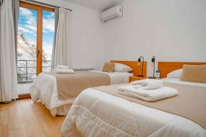 a hotel room with two beds and a window at Hostería Varvarco in Varvarco