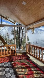 a porch with a rug and a view of the mountains at The magic meadows in Kulu