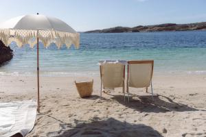 two chairs and an umbrella on a beach at Panorama Rorbusuiter in Steinsland