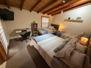 a bedroom with two beds and a desk with a computer at Hostal Senderos del Sur in Freire