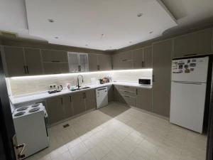 a kitchen with white appliances and a white refrigerator at Izdihar Dalis Suites in Quai