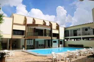 a large building with a swimming pool and white chairs at Veneza Plaza Hotel in Gurupi