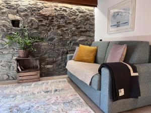 a living room with a blue couch and a stone wall at Little Wild House in Saint Vincent +11 photos