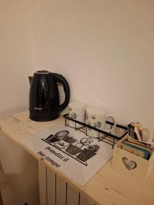 a black tea kettle and three cups on a counter at Ostello di Lussello in Villadeati