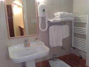 y baño con lavabo, espejo y toallas. en Locanda Il Gallo en Greve in Chianti